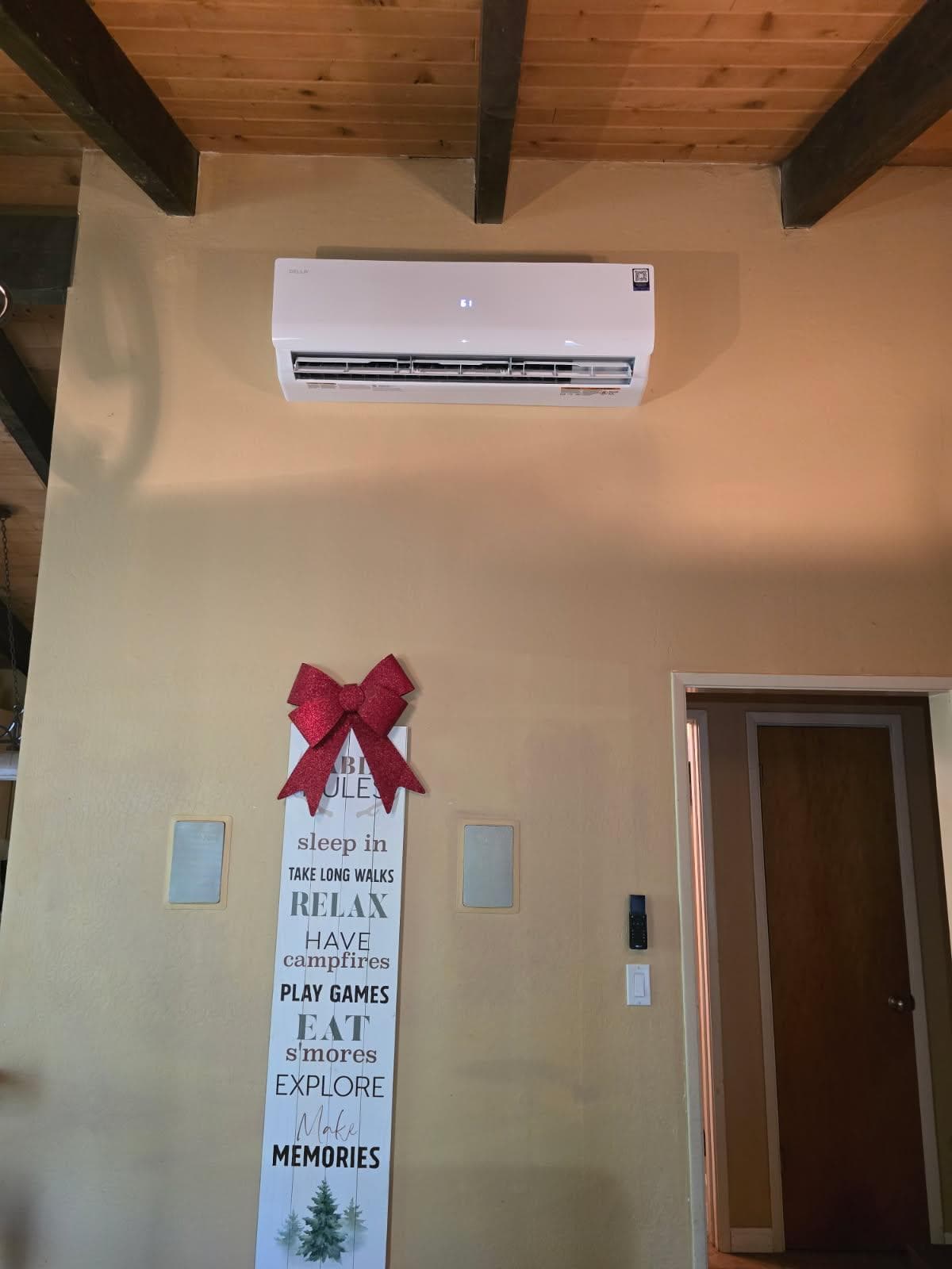 Ductless mini-split head mounted on a cabin wall below exposed beams