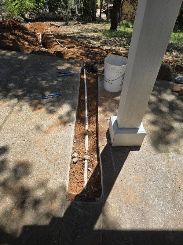 New water line run through a trench cut alongside a concrete porch