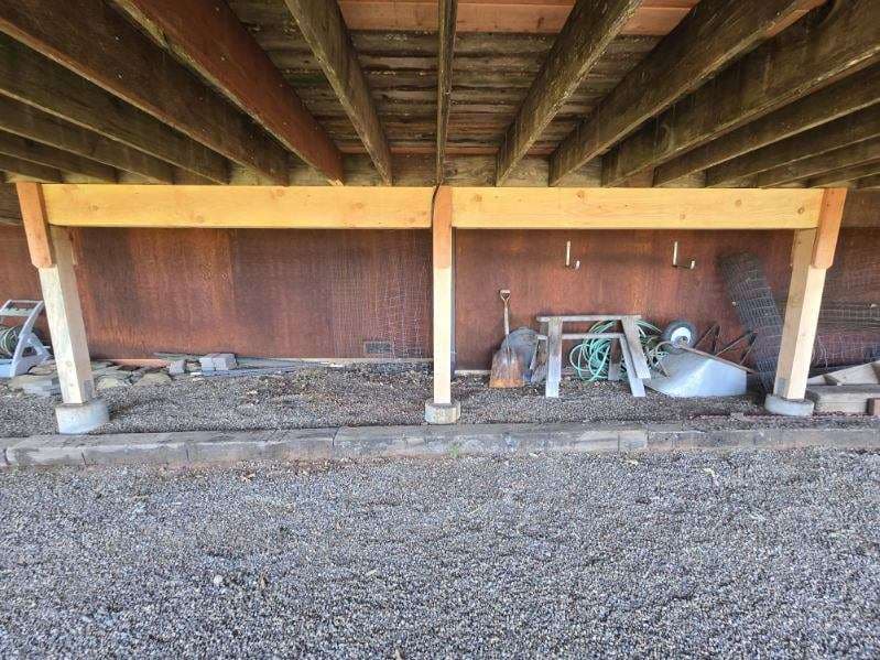 New support beam and posts carrying a cabin floor above a gravel pad
